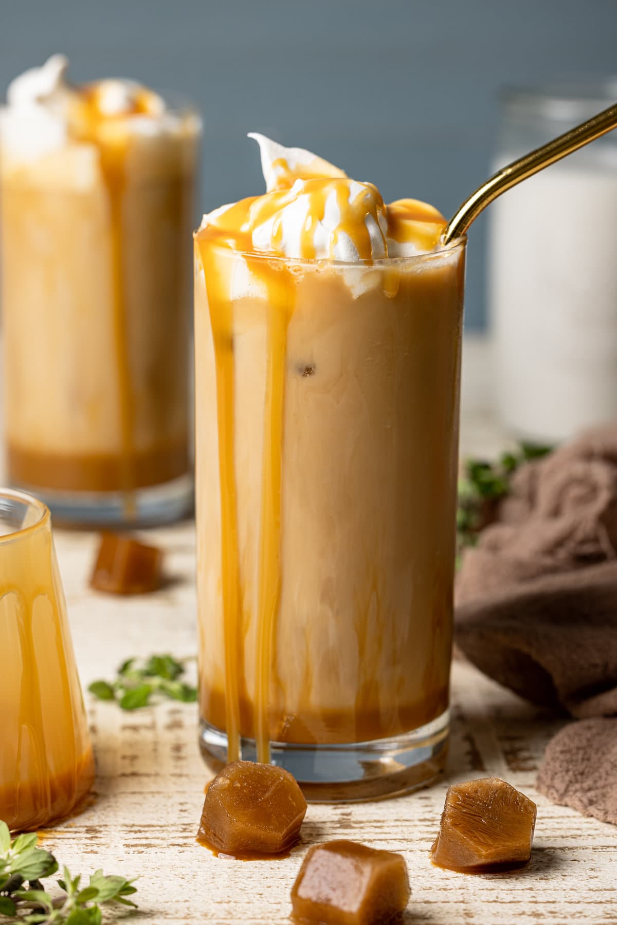 Closeup of an iced caramel latte with caramel dripping down the sides of the glass