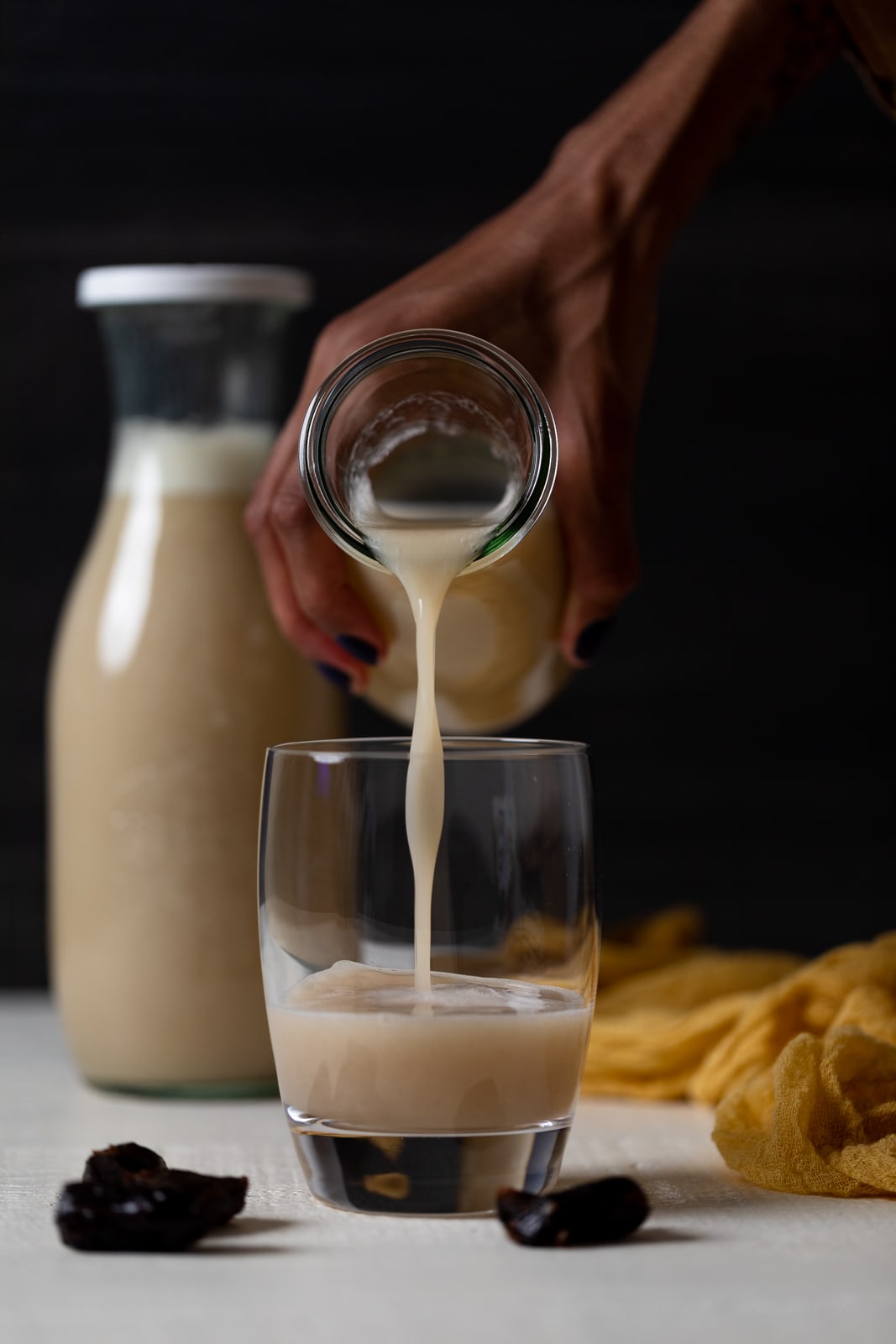Hand pouring a glass jar of cauliflower milk into a glass