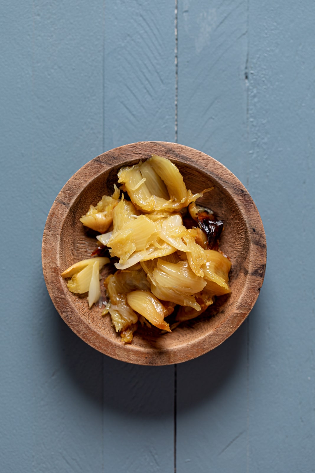 Small wooden bowl of roasted garlic