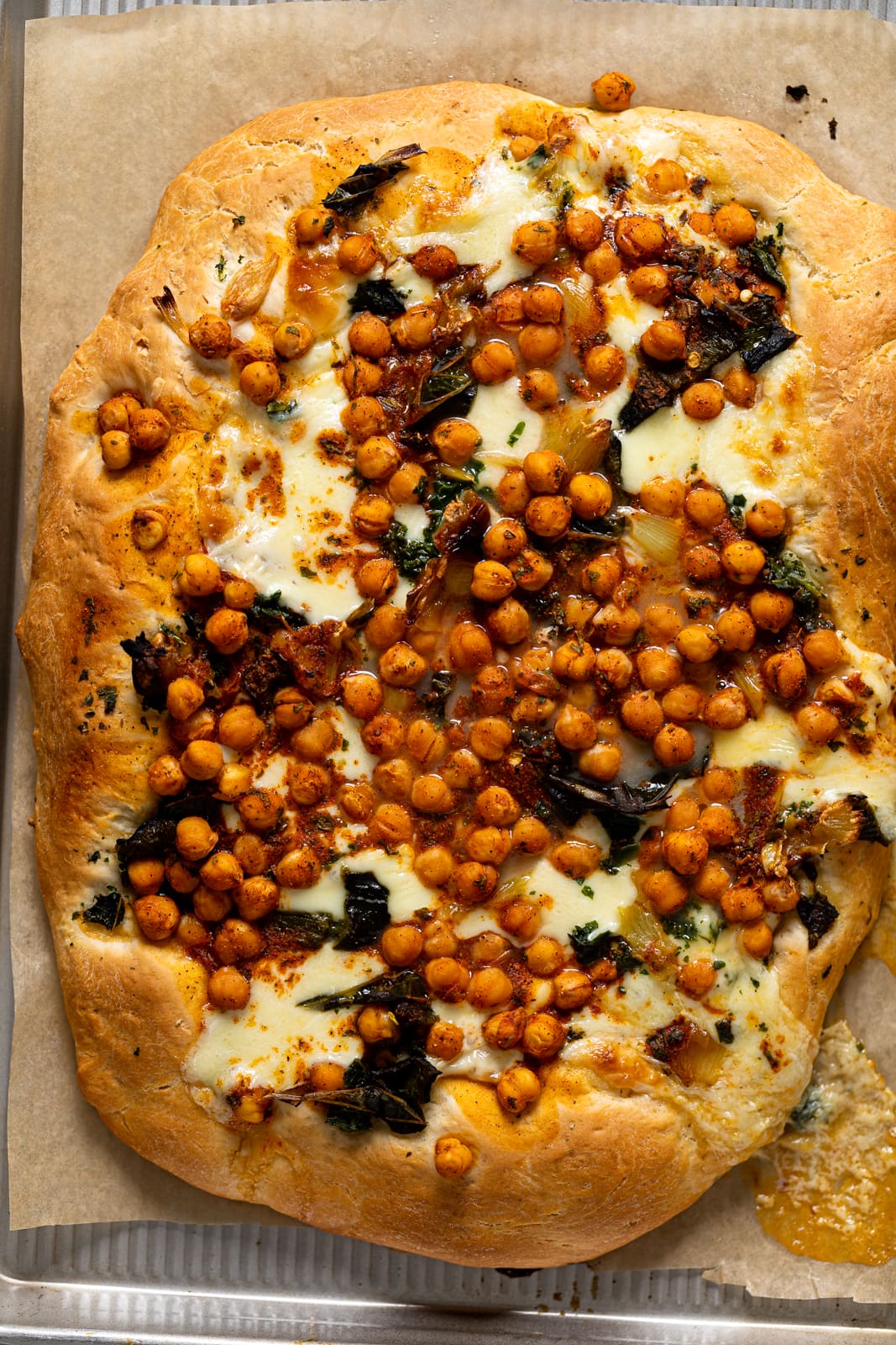 Cooked Sheet Pan Roasted Garlic Buffalo Chickpea Pizza on parchment paper