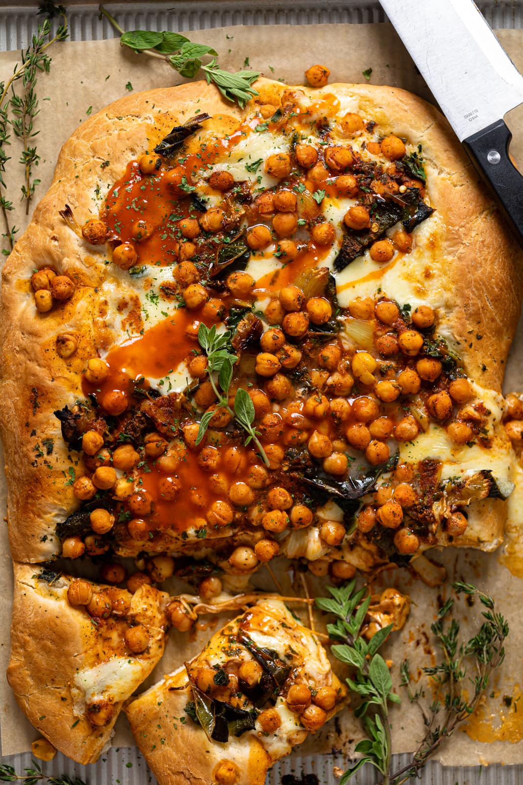Cooked Sheet Pan Roasted Garlic Buffalo Chickpea Pizza with a few slices cut
