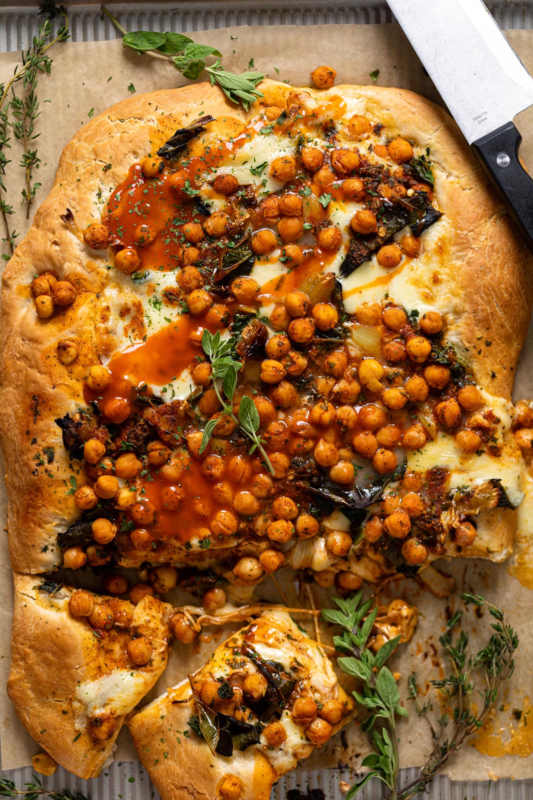 Cooked Sheet Pan Roasted Garlic Buffalo Chickpea Pizza with a few slices cut