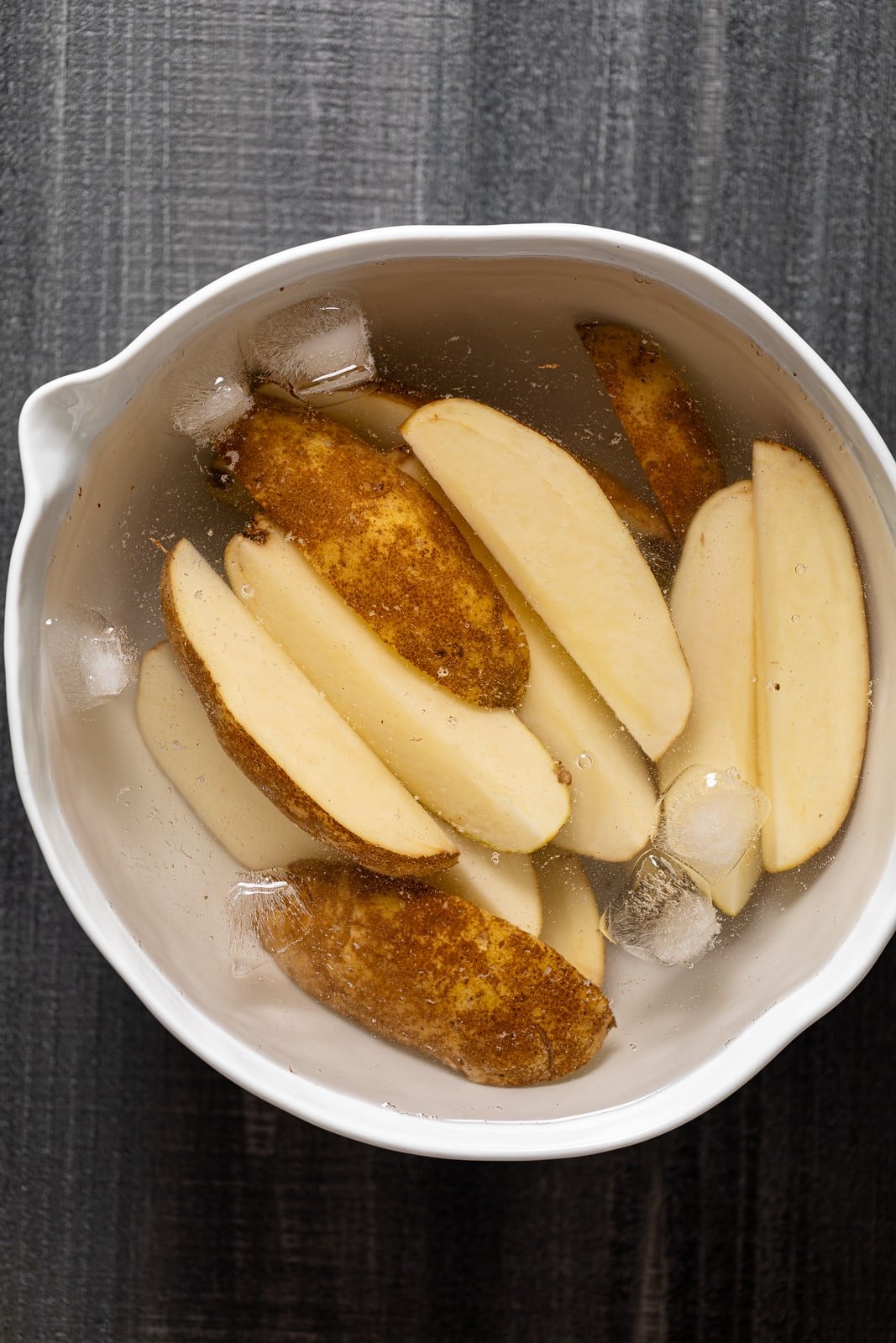 Potato wedges in a bowl of ice water