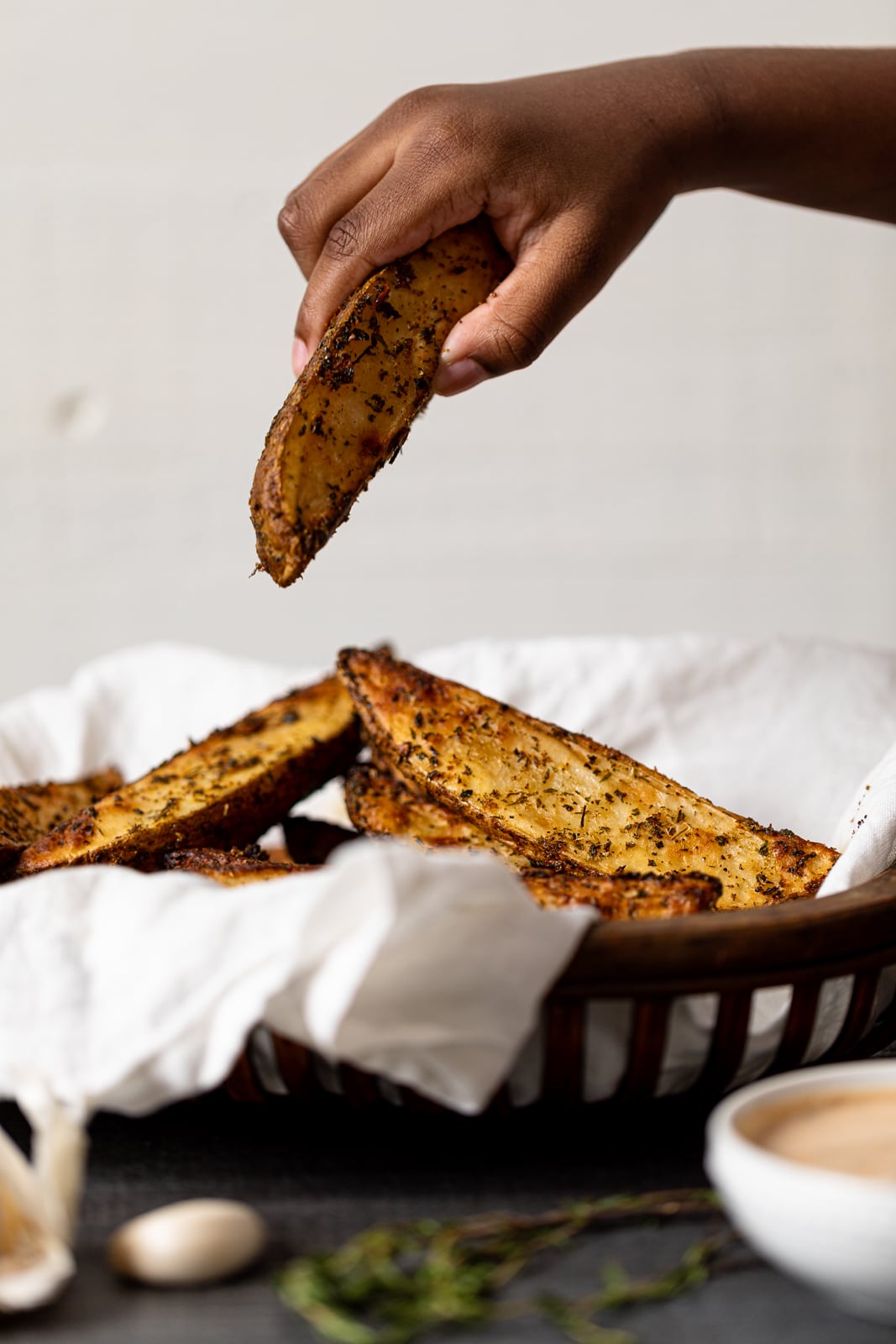 Hand grabbing Crispy Jumbo Garlic Herb Fry from a basket