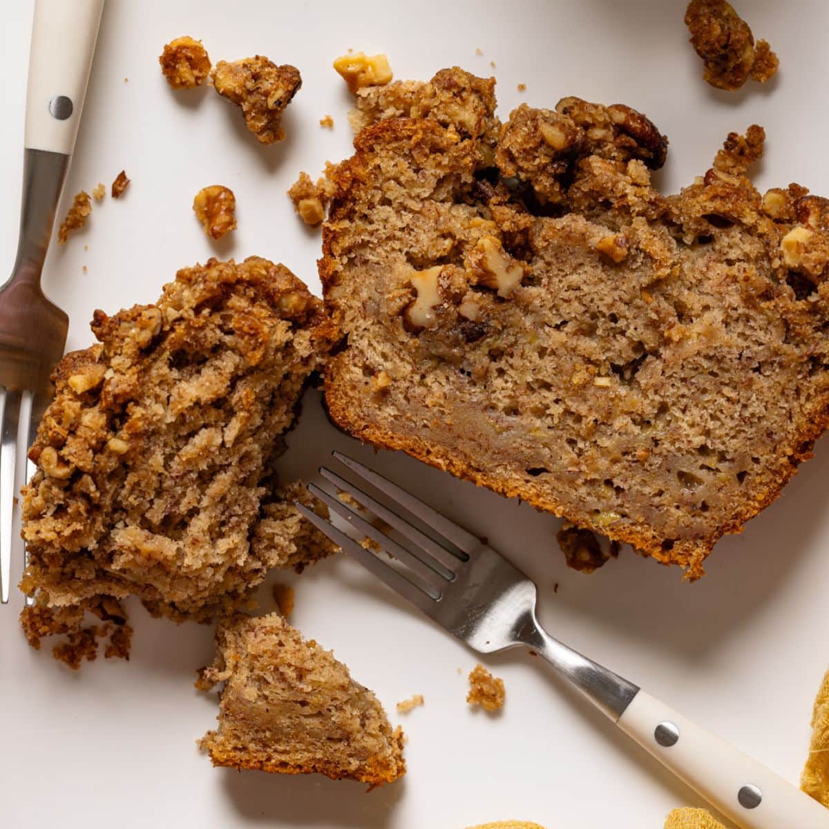 Up close shot of banana bread on a white plate with two forks.