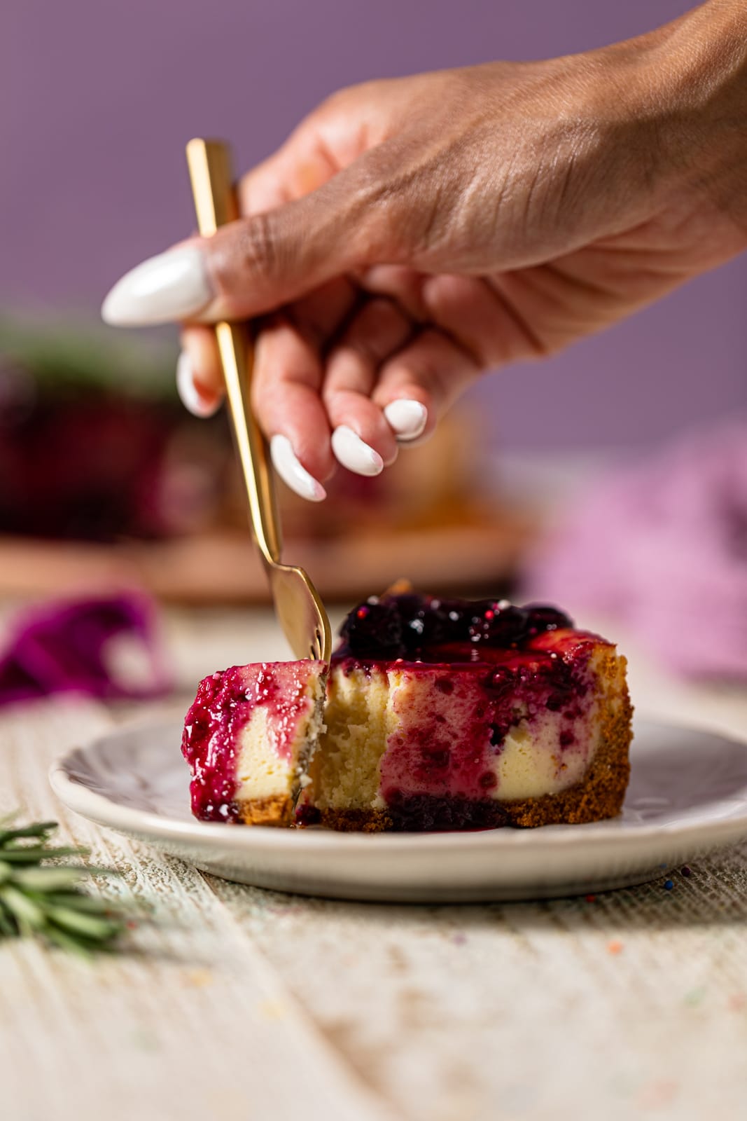 Hand using a fork to take a piece from a slice of Lemon Blueberry Cheesecake