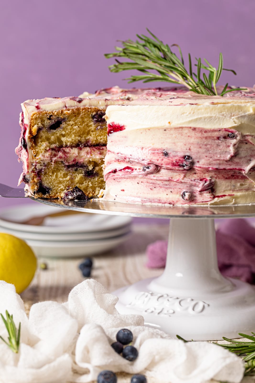 Lemon Blueberry Olive Oil Cake on an elevated platter with slice missing