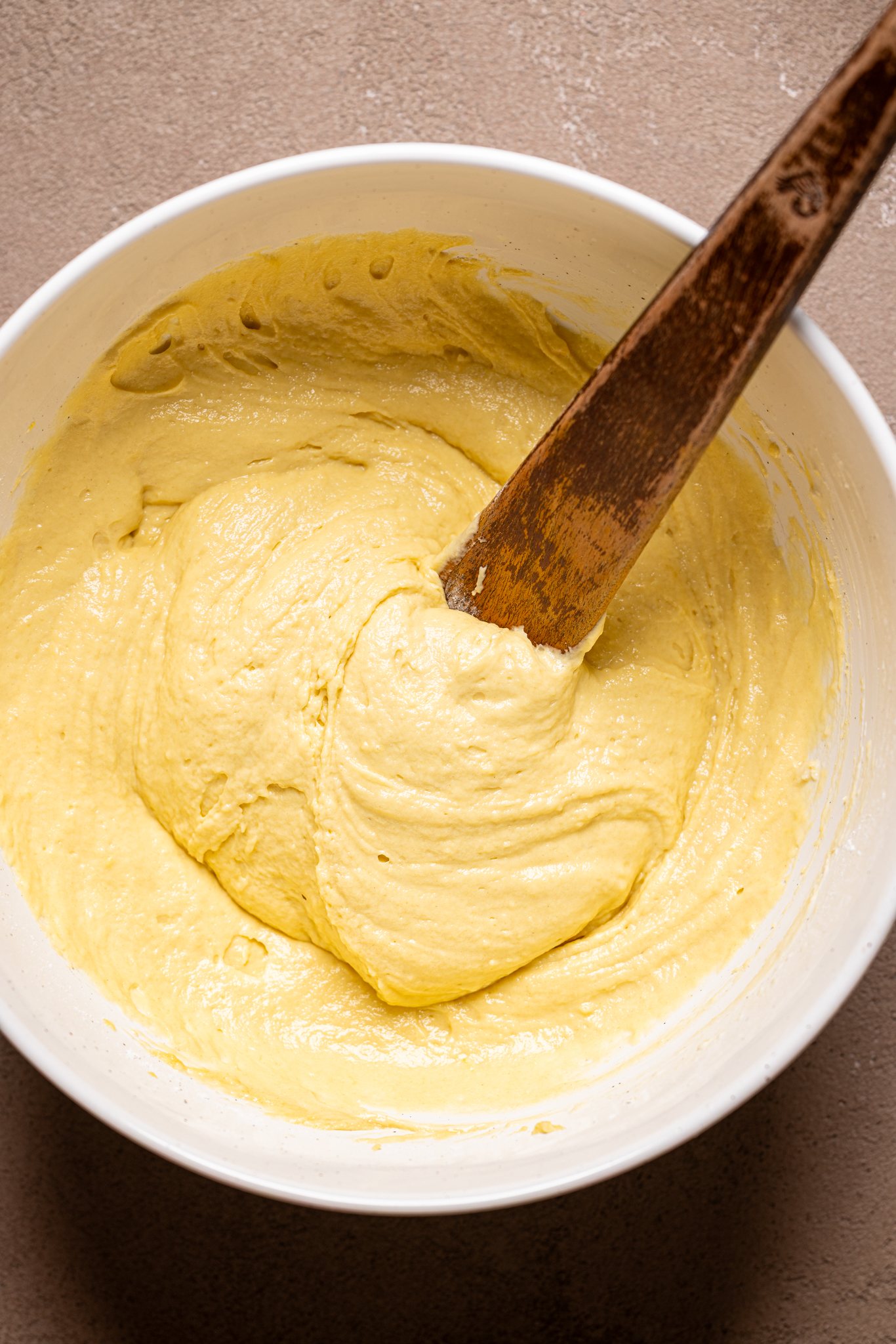 Image of cake batter in a bowl with a wooden spoon.