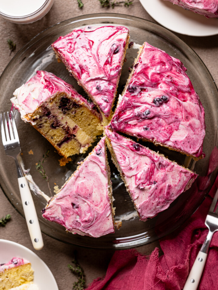 An image of a cake sliced on a cake stand with a fork and plates.
