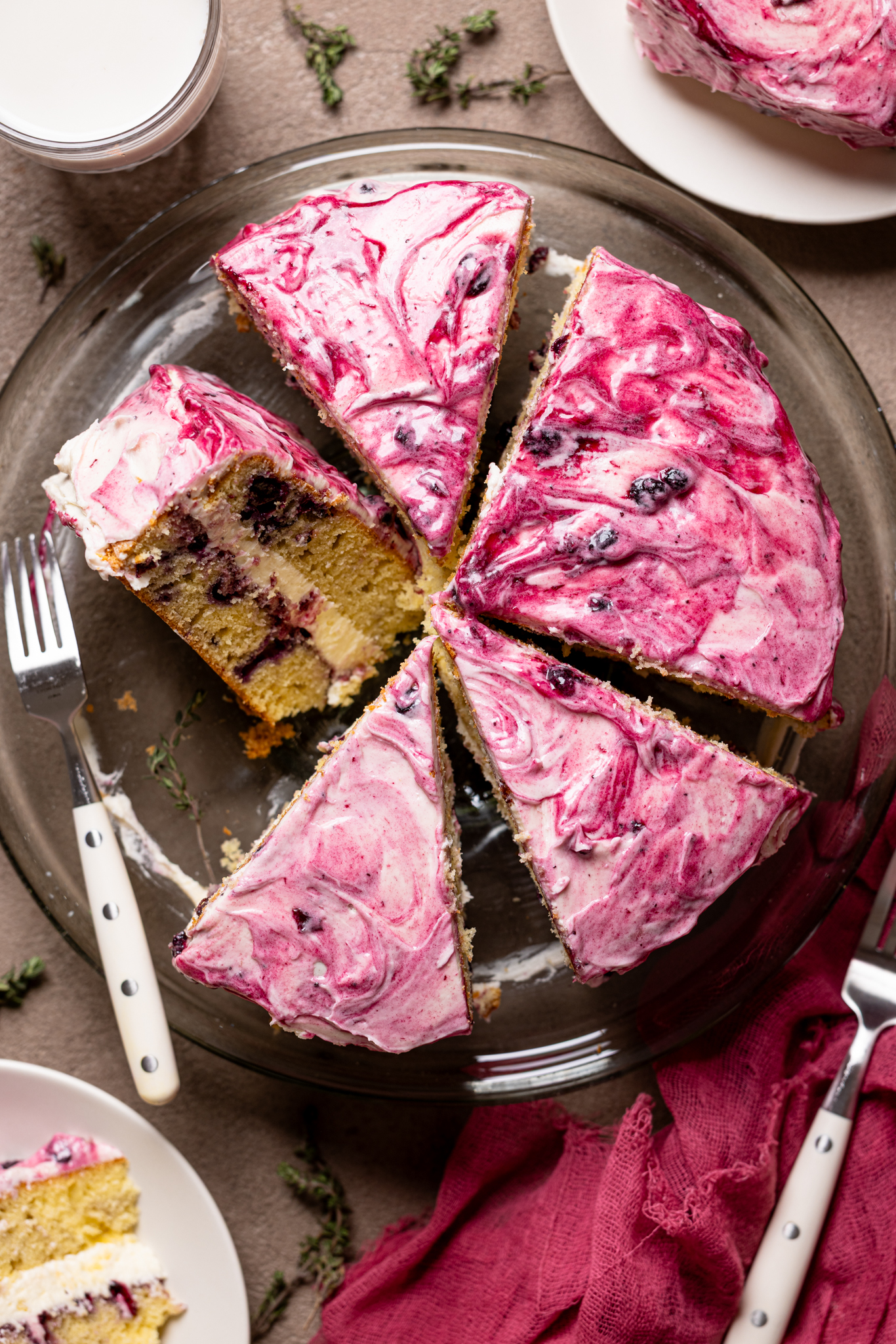 An image of a cake sliced on a cake stand with a fork and plates.