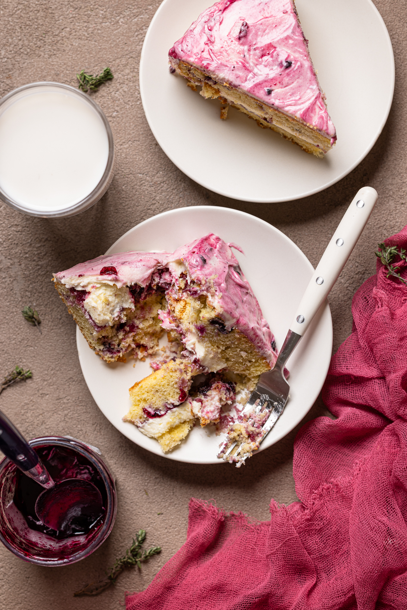 An image of two plates with cake slices and a side of milk with a fork.