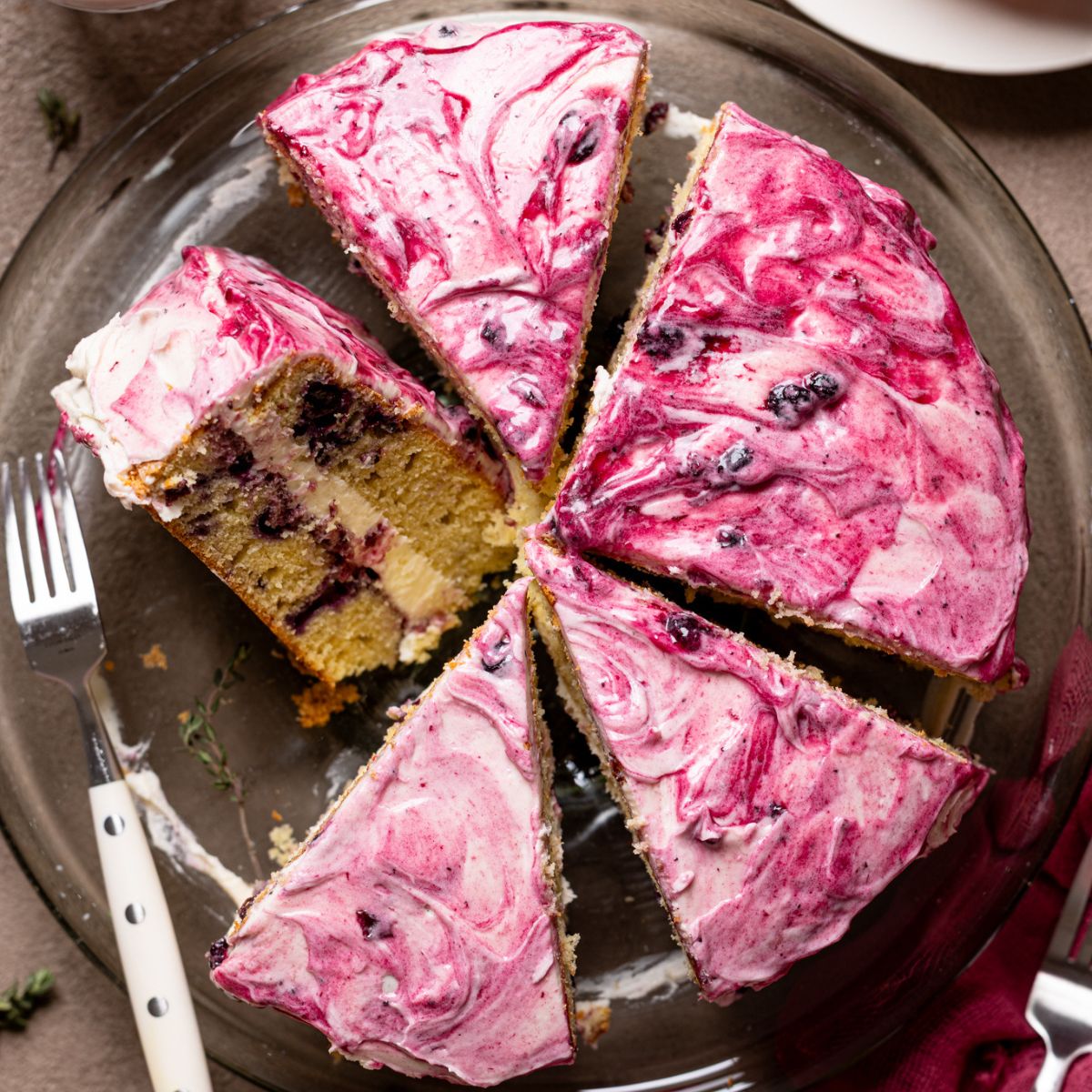 An image of a cake sliced on a cake stand with a fork and plates.