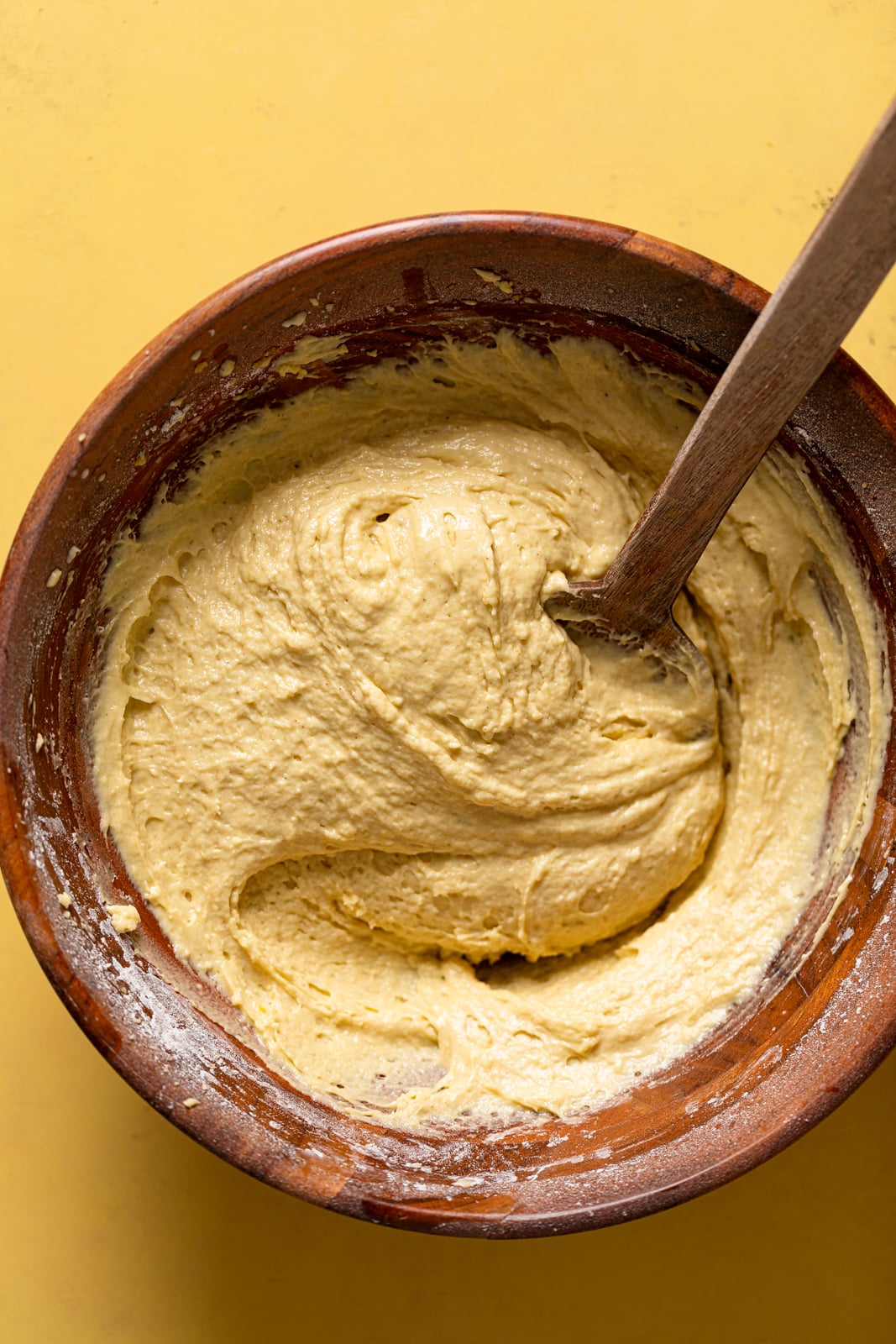 Wooden spoon stirring a bowl of Lemon Ginger Bundt Cake batter