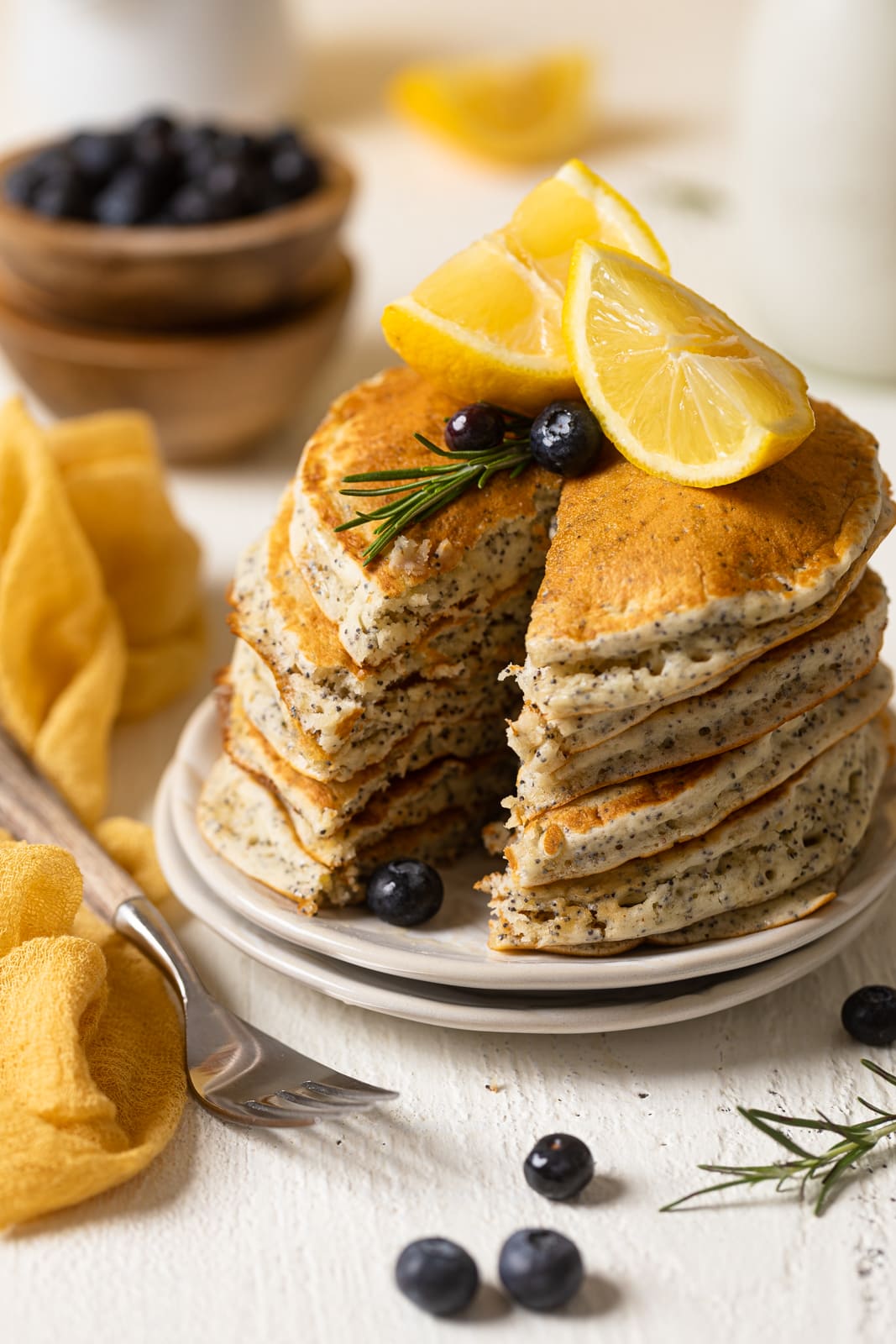 Stack of Vegan Lemon Poppyseed Pancakes with a slice missing