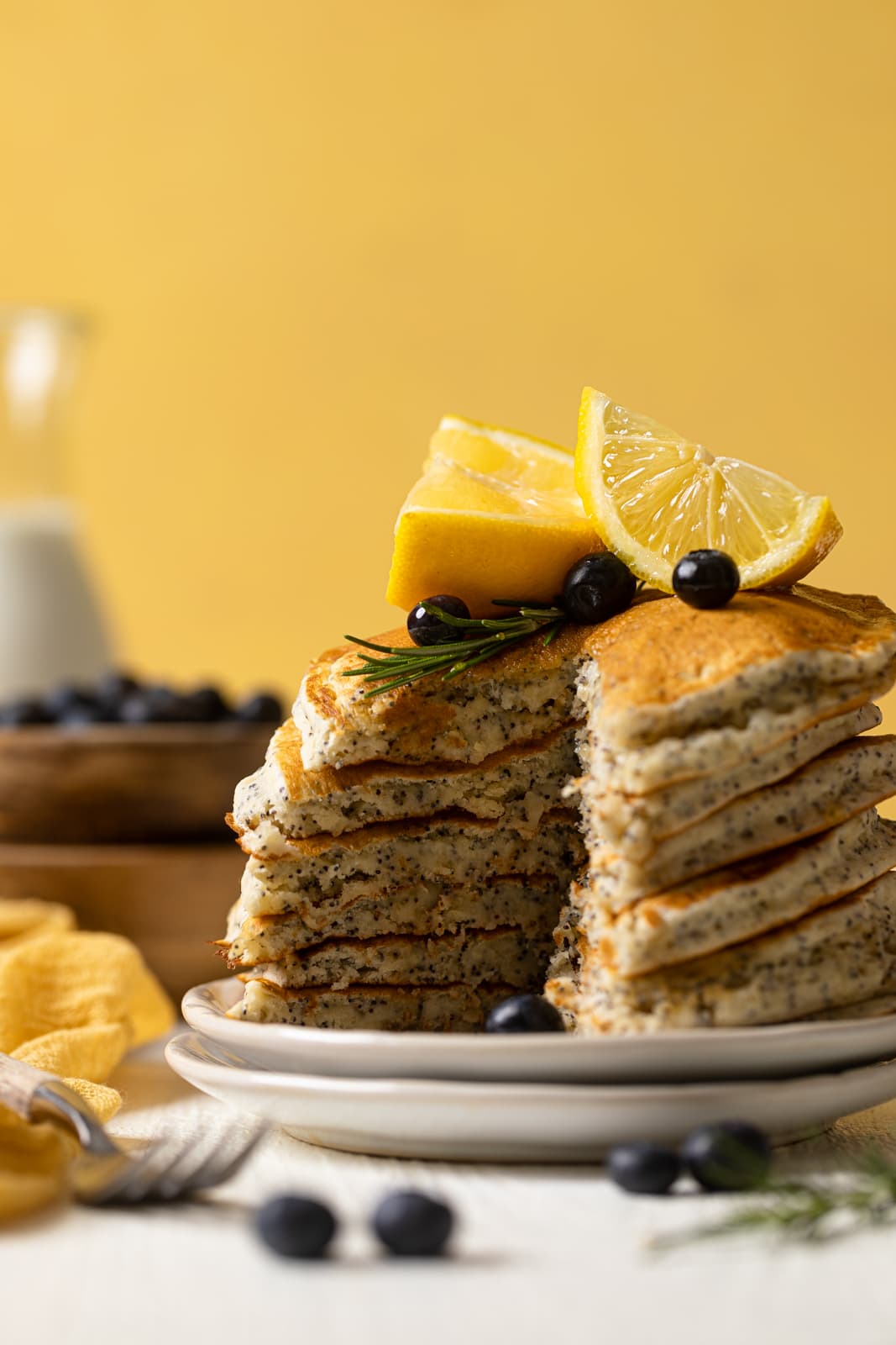 Stack of Vegan Lemon Poppyseed Pancakes with a slice missing