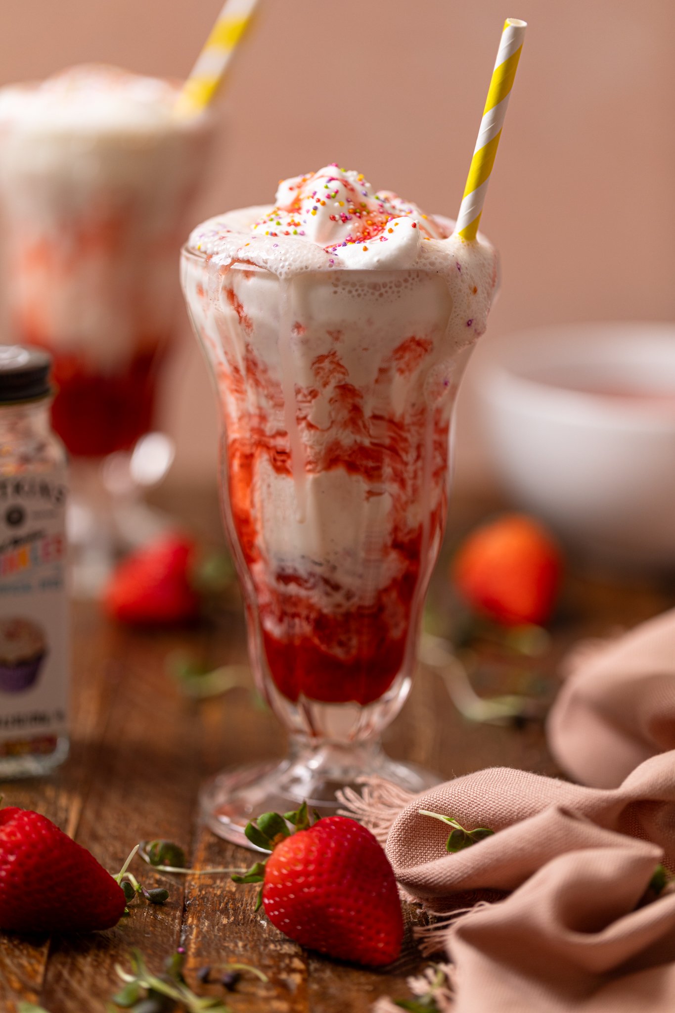 Dairy-free strawberry milkshake in two glasses with straws and strawberries.