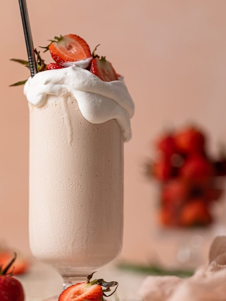 Glass overflowing with Dairy-Free Strawberry Milkshake