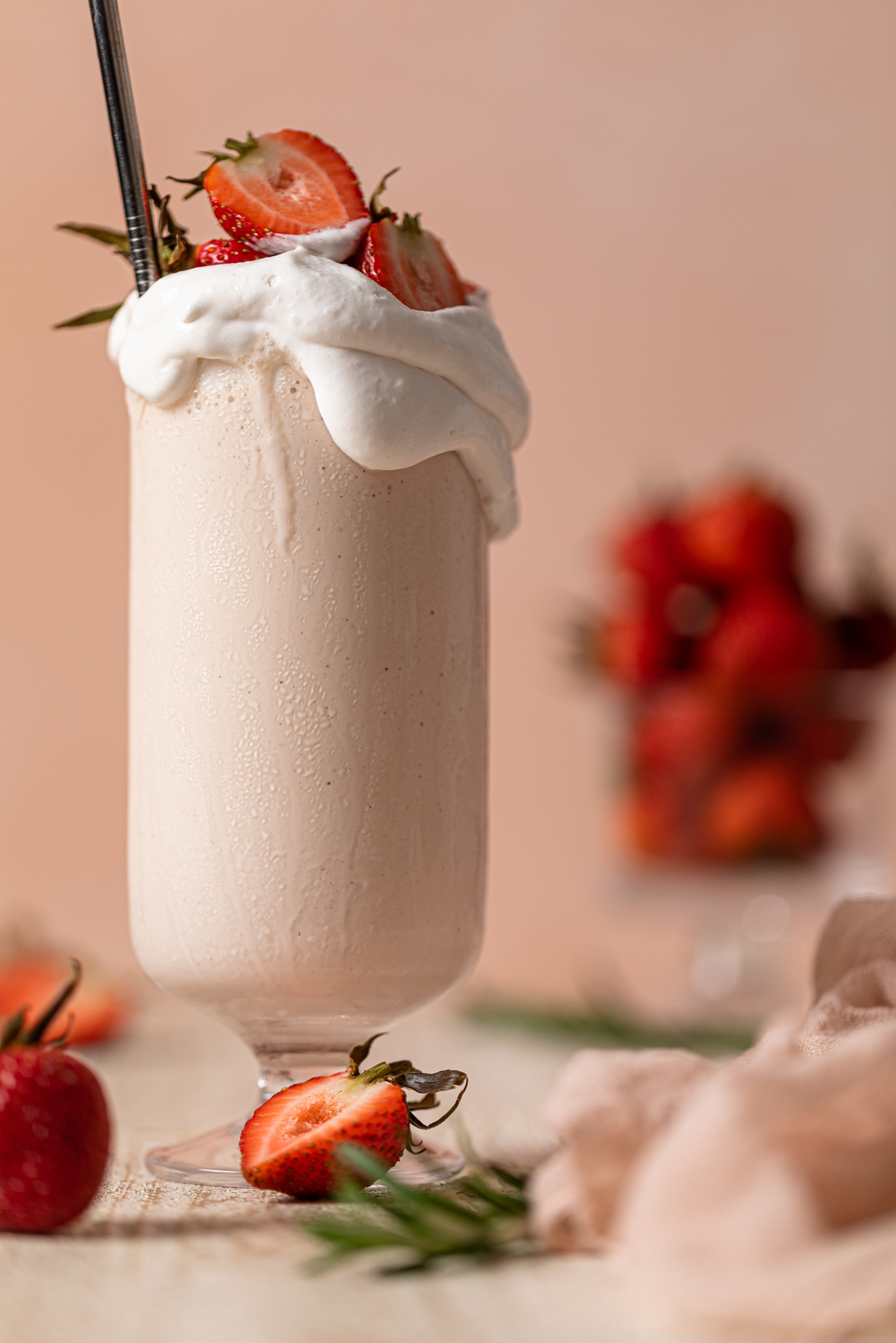 Glass overflowing with Dairy-Free Strawberry Milkshake with a straw