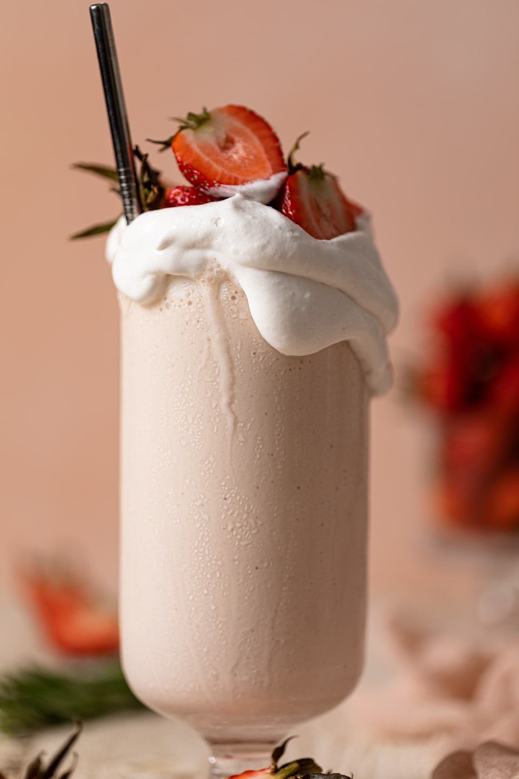 Closeup of a glass overflowing with Dairy-Free Strawberry Milkshake