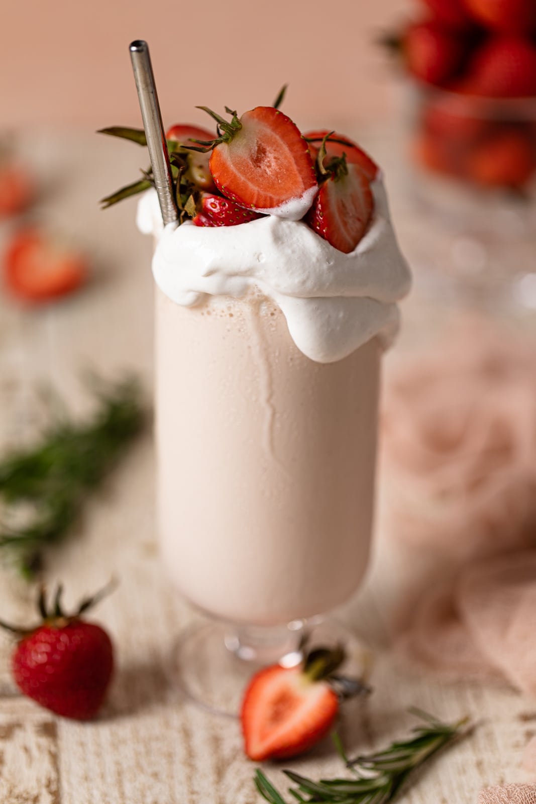 Glass of Dairy-Free Strawberry Milkshake topped with strawberries and coconut whipped cream
