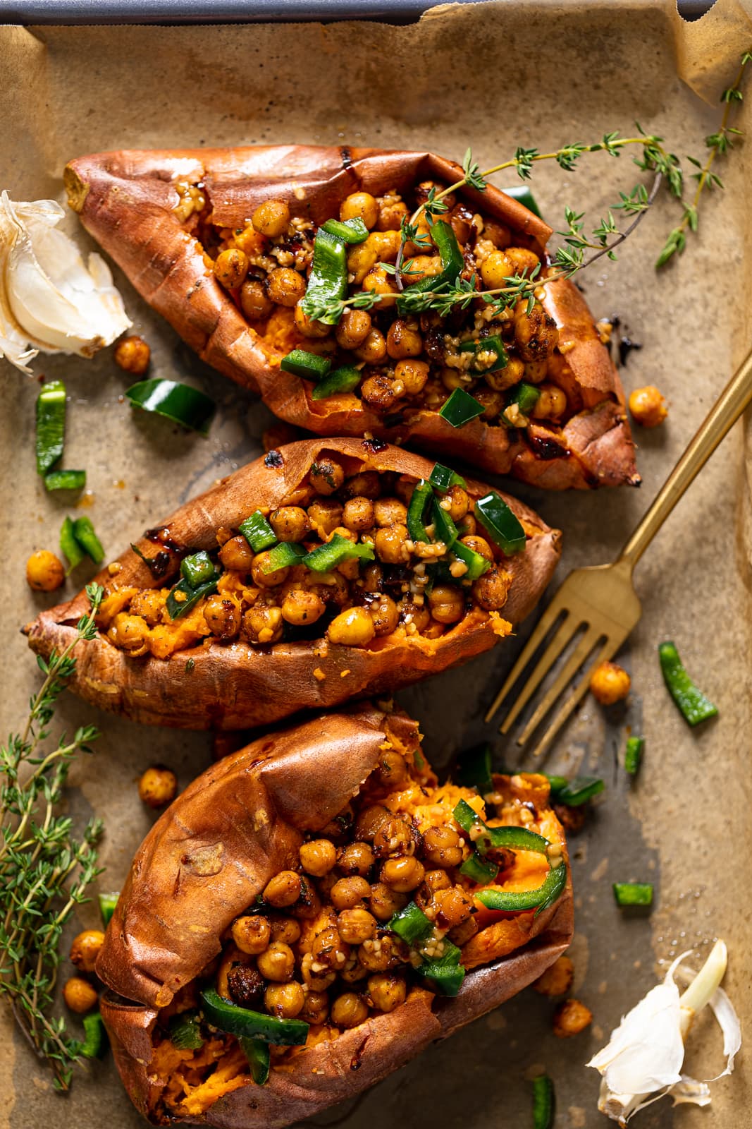 Three Spiced Chickpea Stuffed Sweet Potatoes with a fork on parchment paper