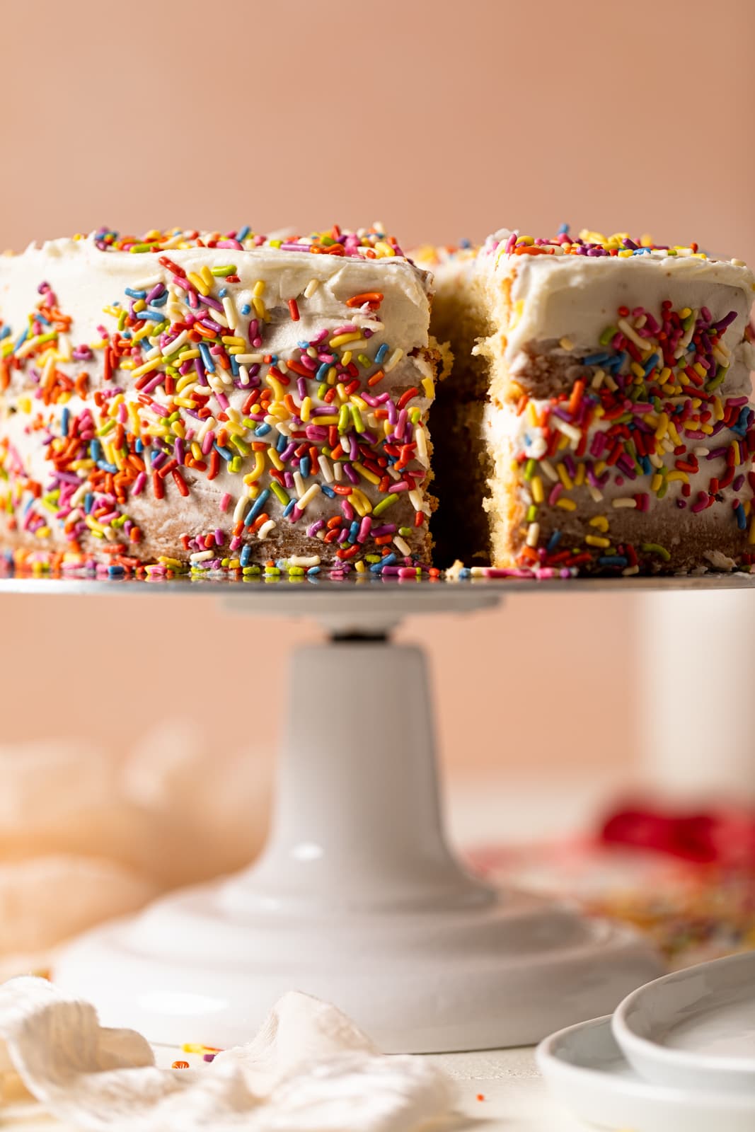Vanilla Yogurt Cake with Sprinkles on an elevated serving platter a slice pulled out