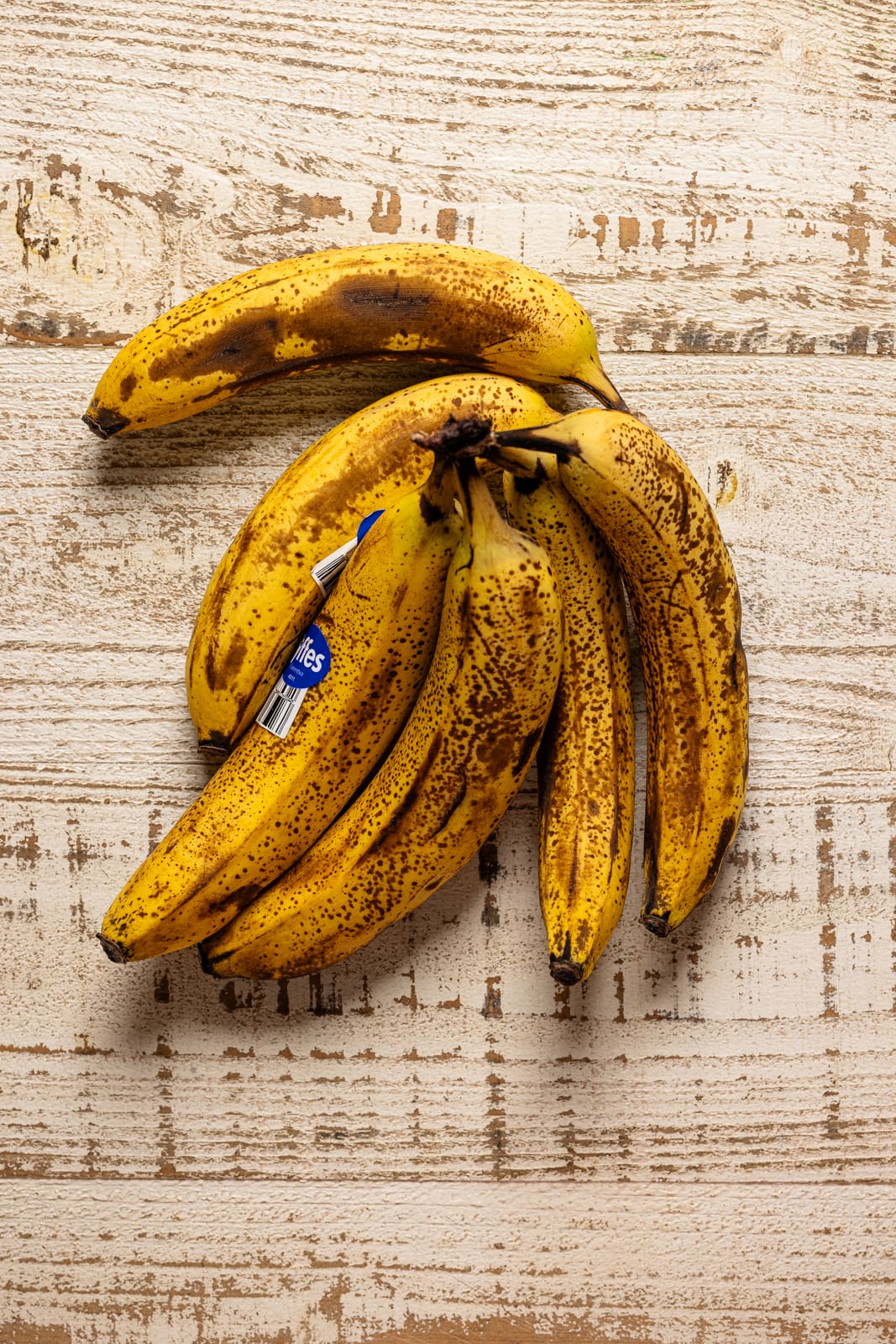 Ripe bananas on a white wood table.