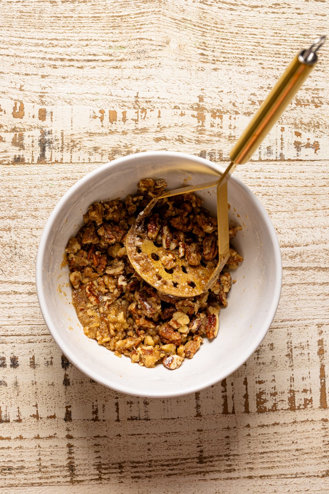 Toppings crushed in a white bowl with a masher.