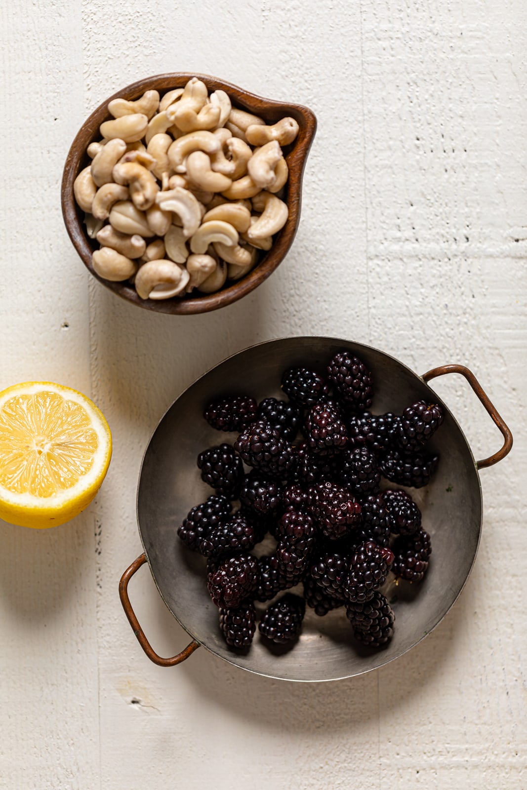 Bowl of cashews and blackberries near a lemon half