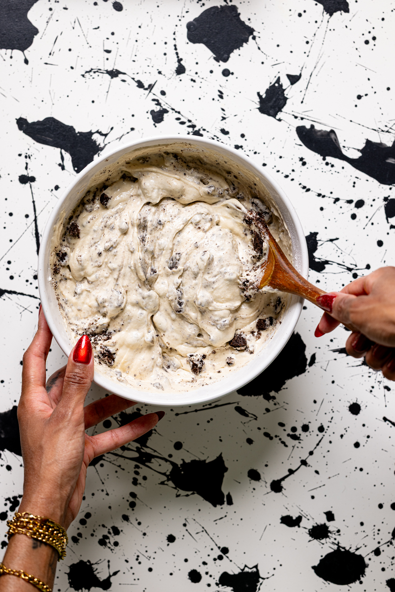 Cake batter being mixed with a wooden spoon with women hands.
