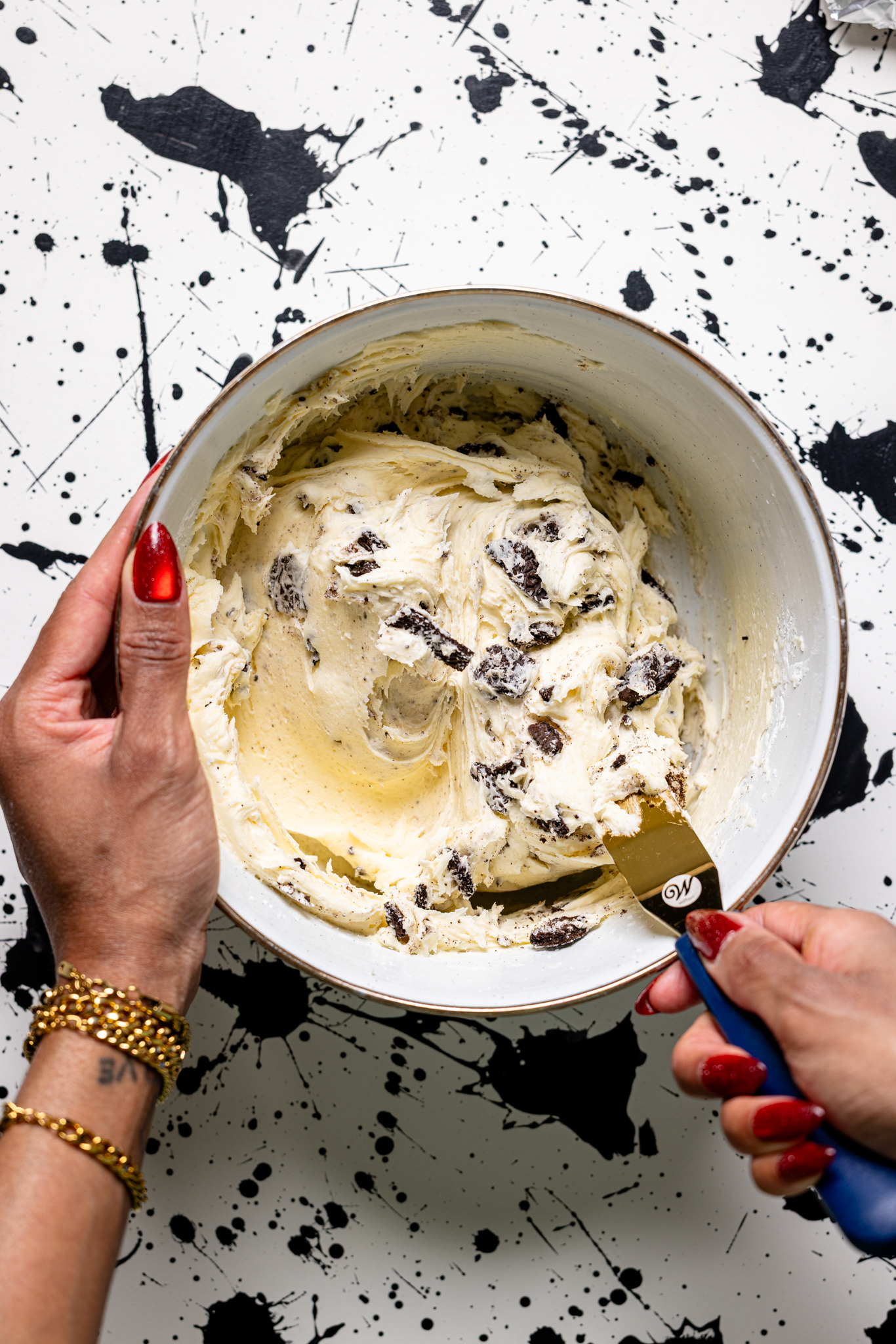 Buttercream with crushed Oreo cookies being stirred by women hands.