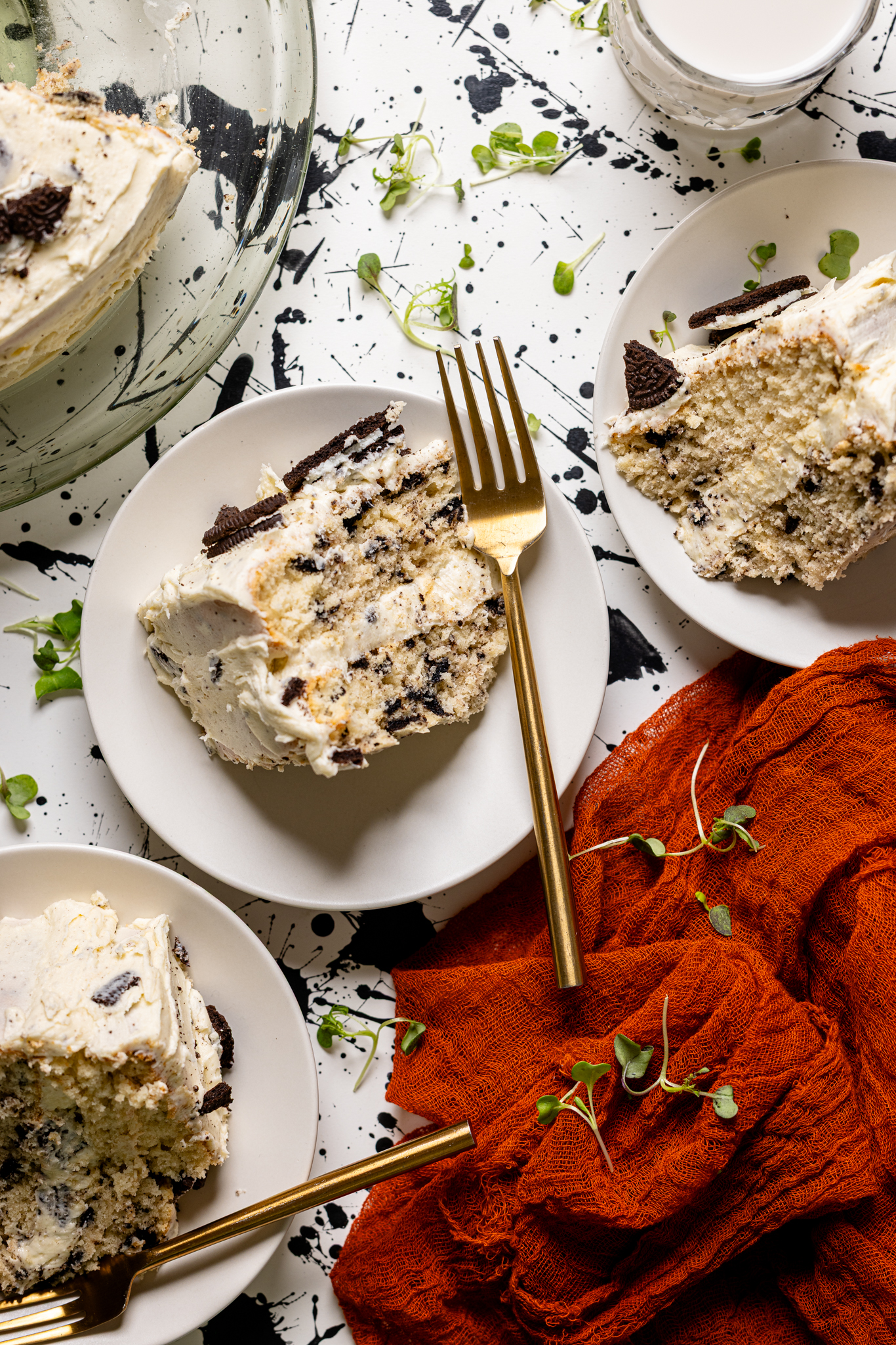 Image of three plates with Oreo cake slices on a black and white table with a red napkin.