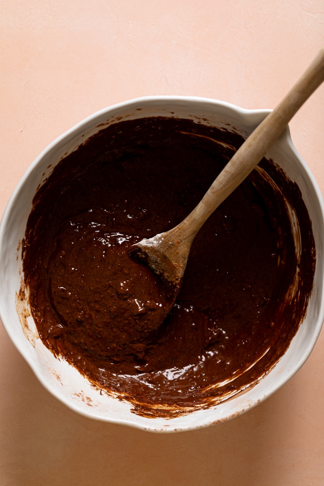 Wooden spoon stirring a bowl of Vegan Zucchini Brownie batter