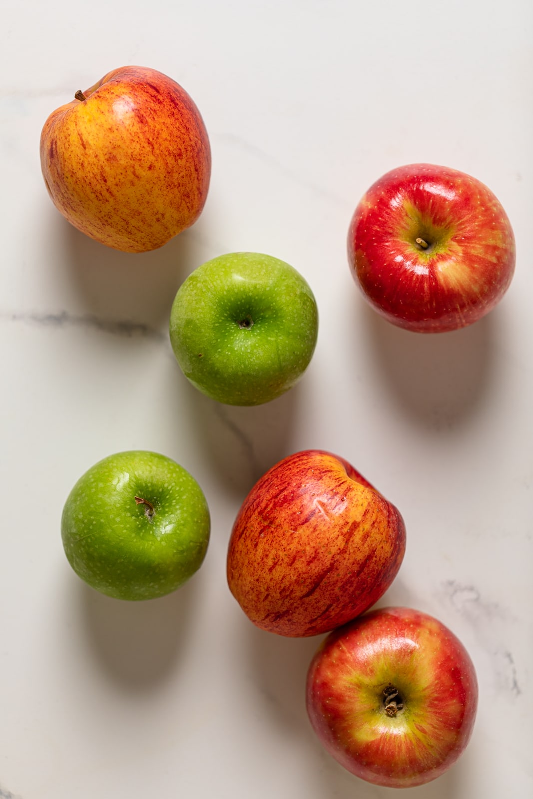 Green and red apples on a marble surface