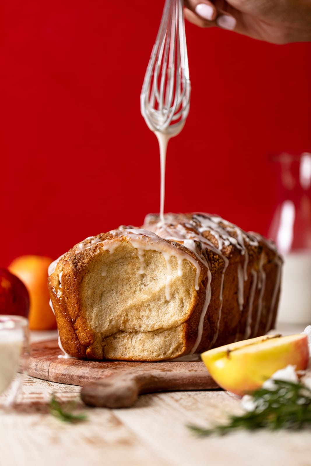Whisk dripping glaze on a loaf of Vegan Apple Cinnamon Pull-Apart Bread