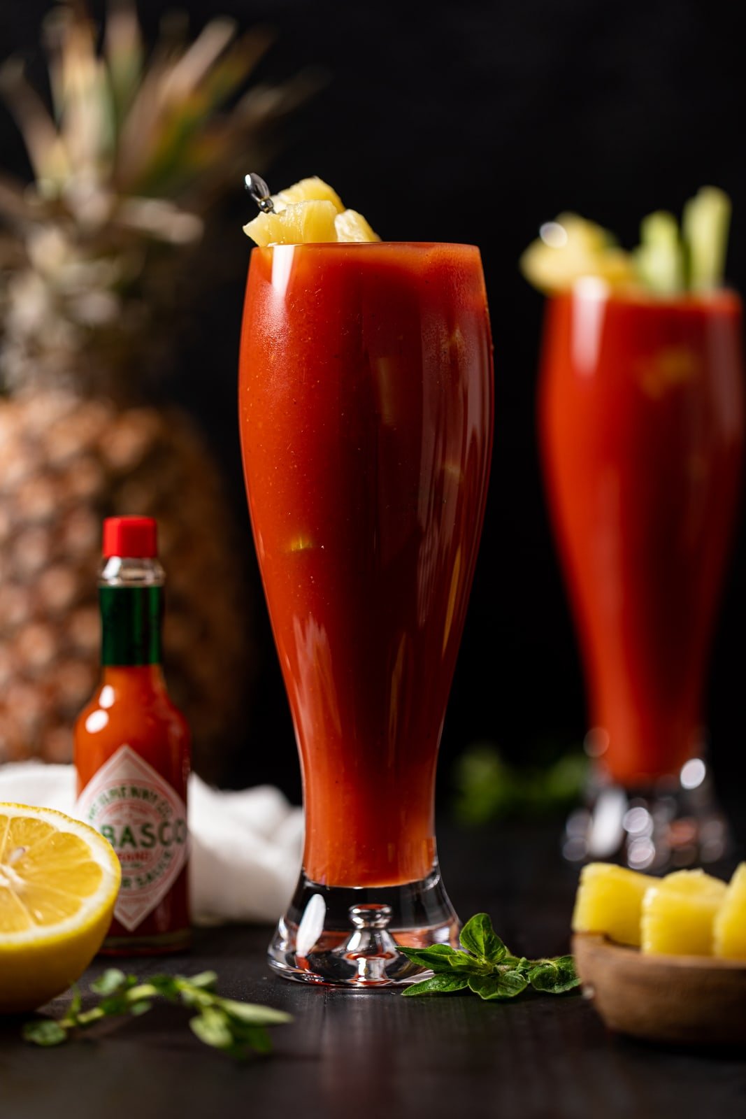 Two tall Bloody Mary Mocktails next to a jar of Tabasco sauce