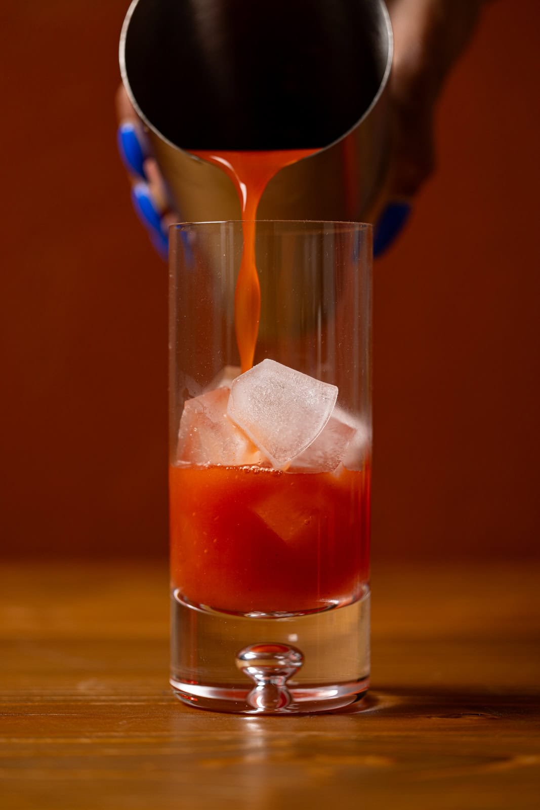 Mocktail being poured in a glass over ice.
