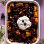 Baking pan of Blueberry Pie French Toast Casserole topped with coconut whipped cream
