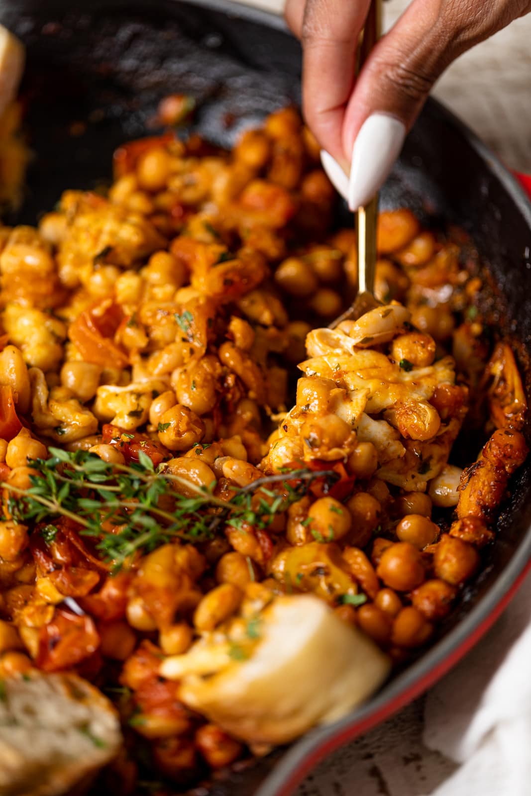 Closeup of a spoon scooping Saucy Baked Chickpea and White Beans