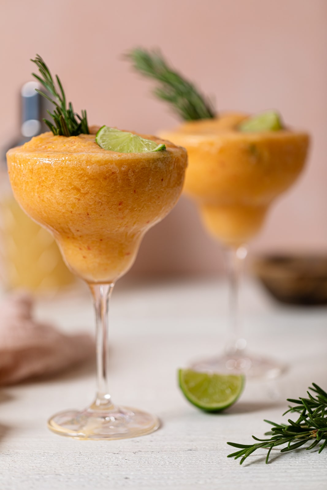 Two long-stemmed glasses of Frozen Peach Lime Margarita Mocktail