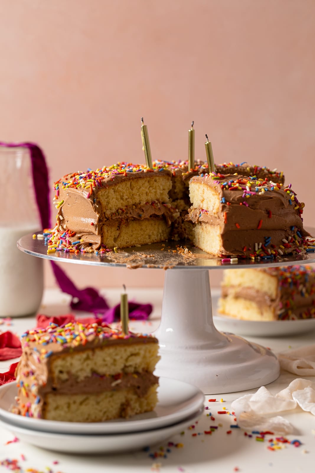 Sliced Vanilla Birthday Cake with Chocolate Frosting on an elevated serving platter