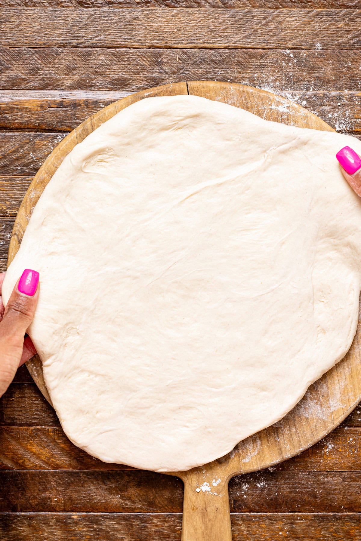 Pizza crust being stretched with hands.
