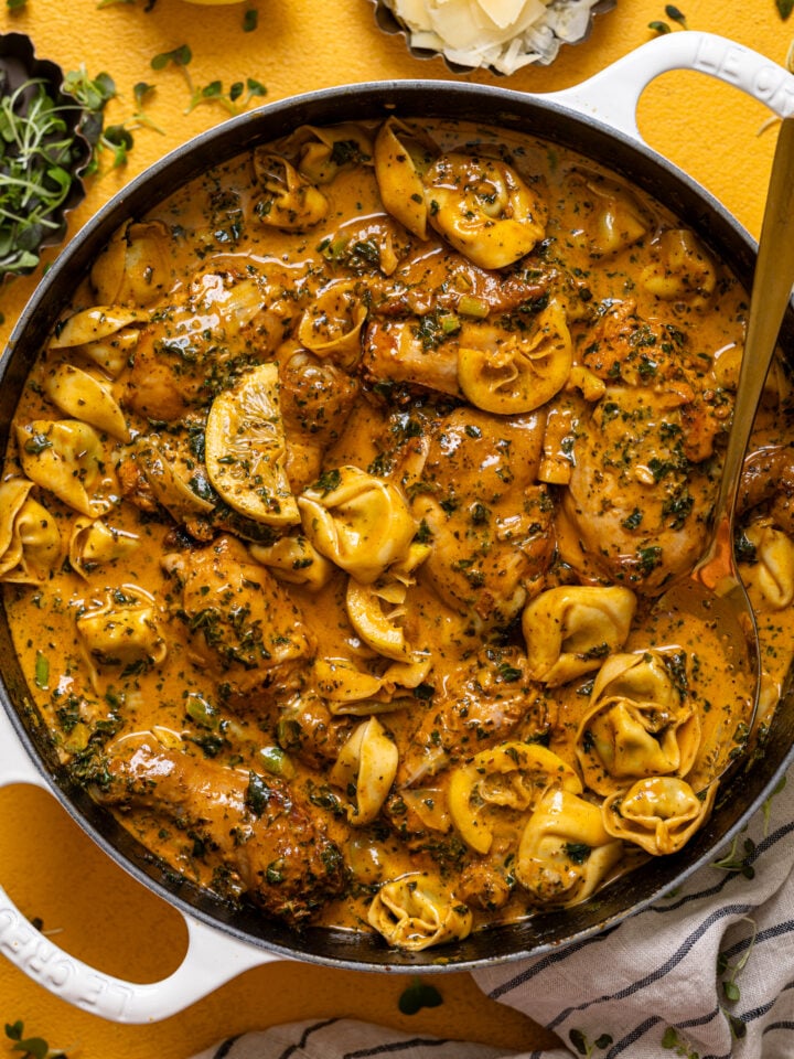 Creamy Lemon Garlic Herb Chicken with Tortellini in a skillet with a spoon.
