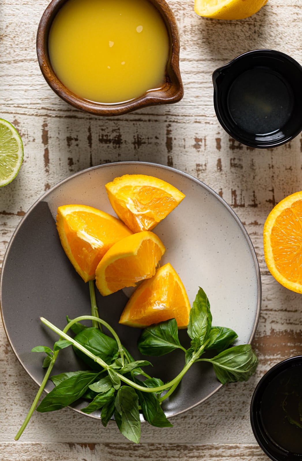Ingredients for Orange Crush Mocktail with Basil including orange, basil leaves, and lime