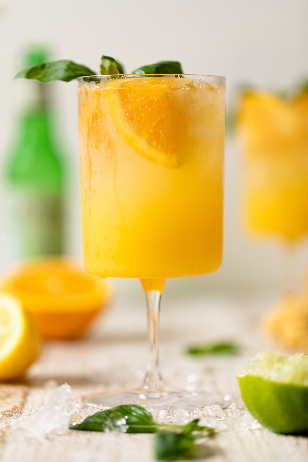 Bright Orange Crush Mocktail with Basil in a long-stemmed glass