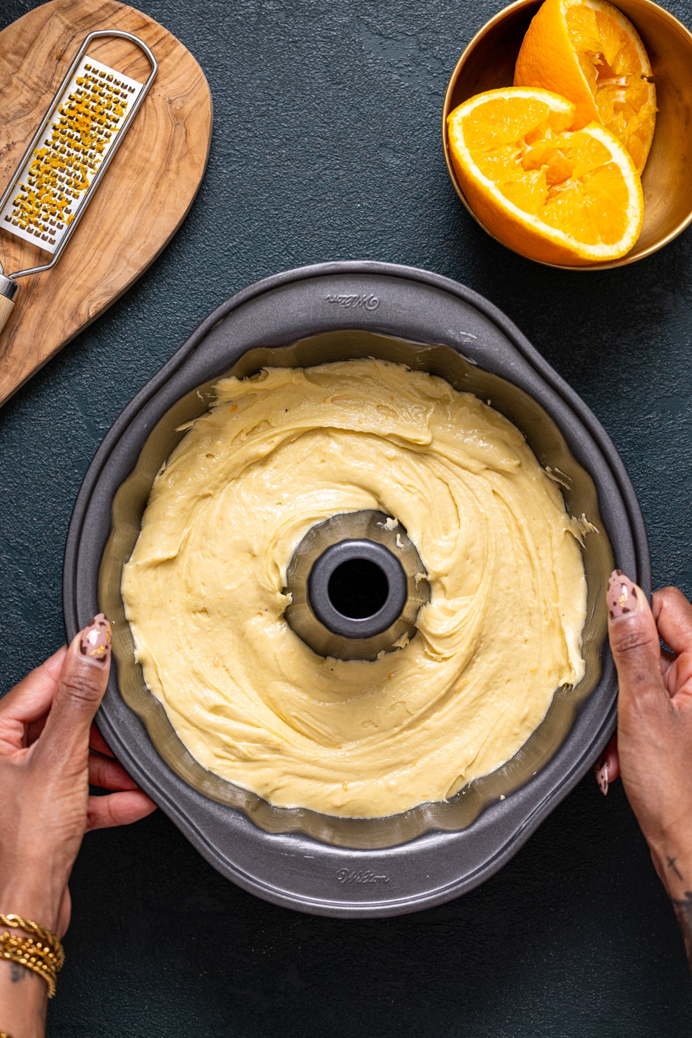 Cake batter in a bundt pan being held by woman hands.