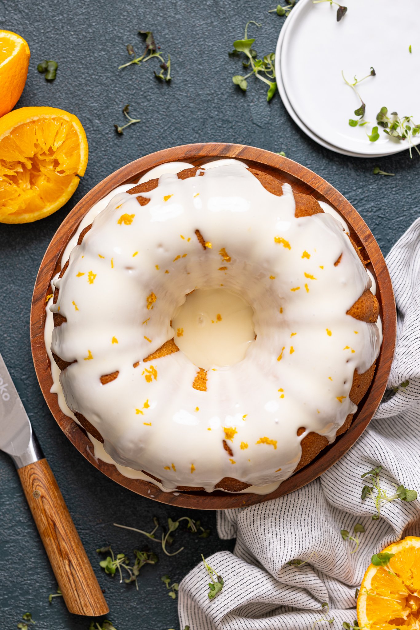 Orange Olive Oil Bundt Cake on a cake stand on a hunter green table.
