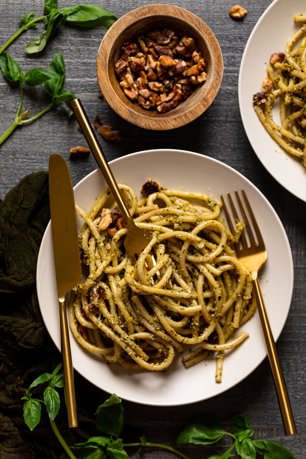 Plate of Walnut Pesto Bucatini Pasta next to a bowl of walnuts