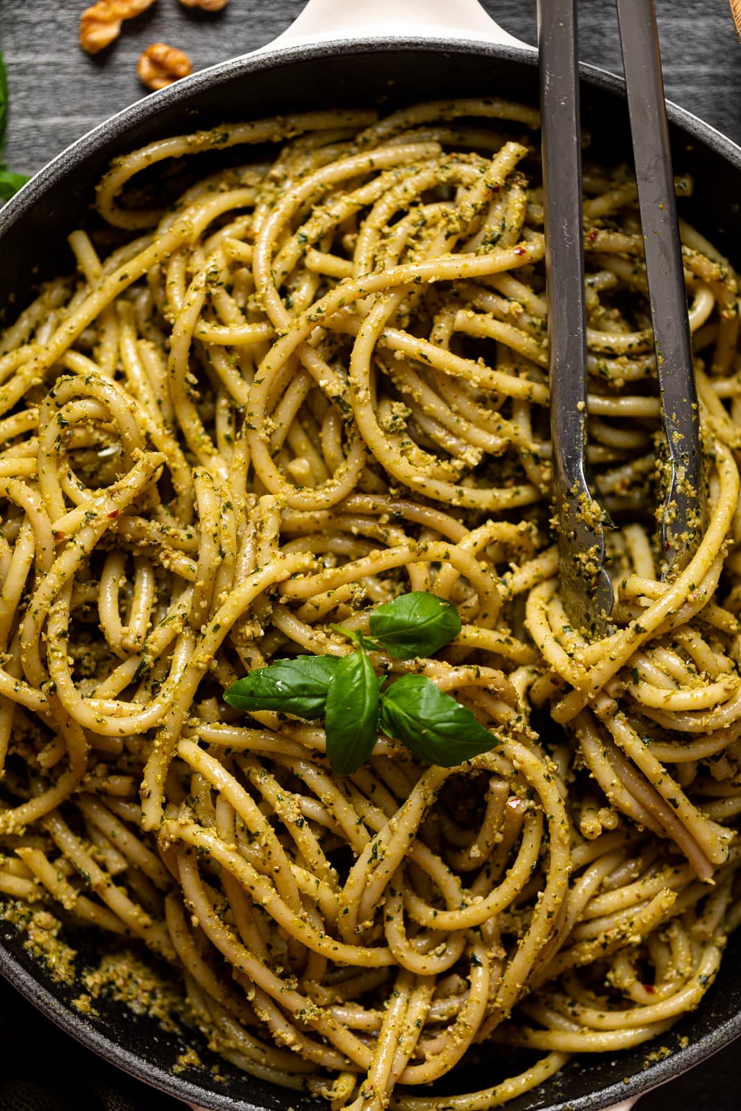 Closeup of tongs grabbing Walnut Pesto Bucatini Pasta