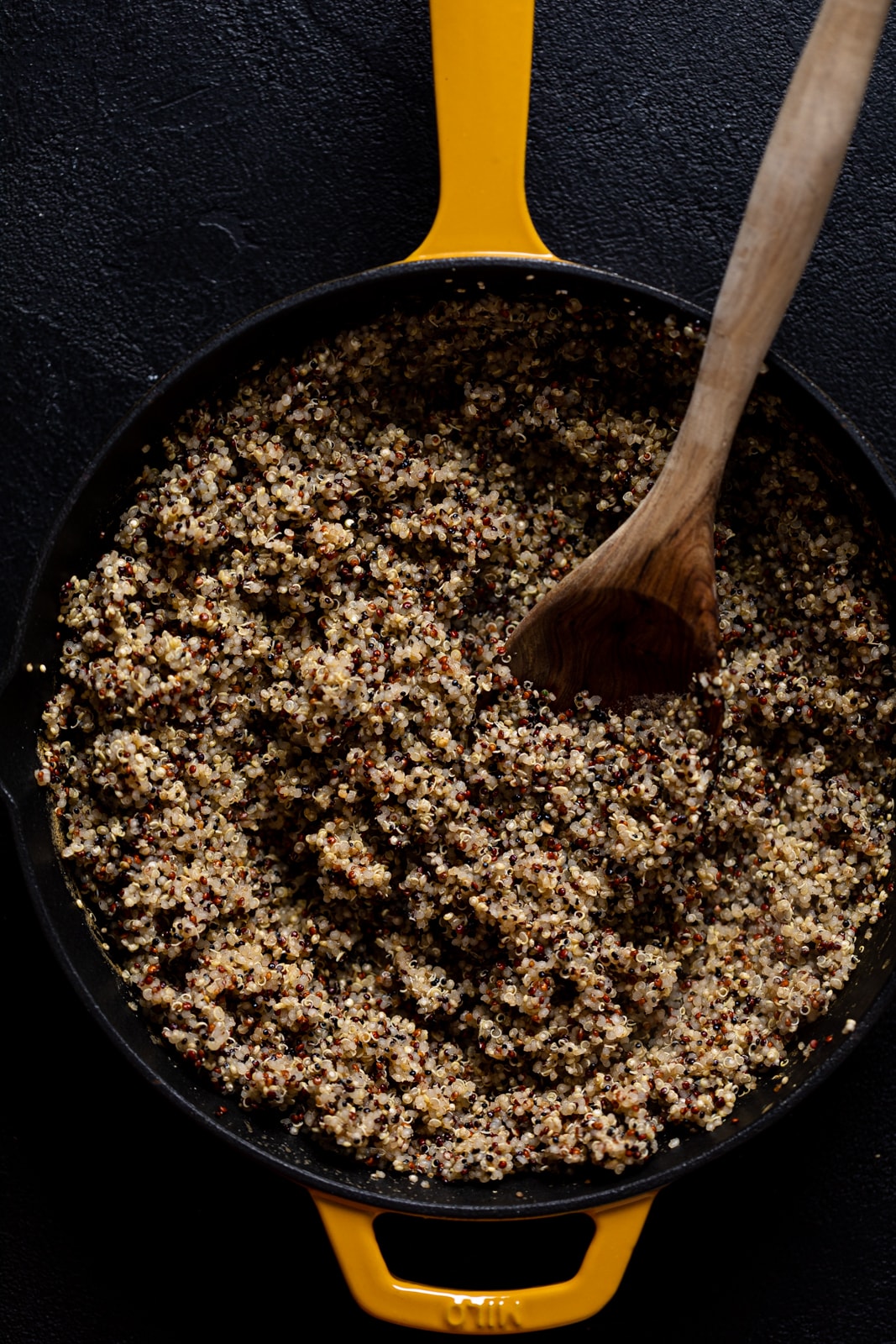 Wooden spoon stirring a skillet of quinoa